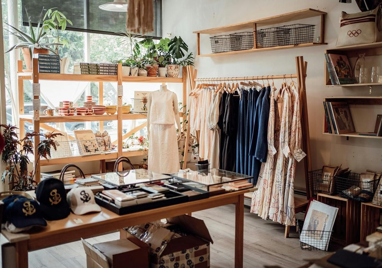 A clothing store interior featuring shelves filled with various clothes and books for sale.